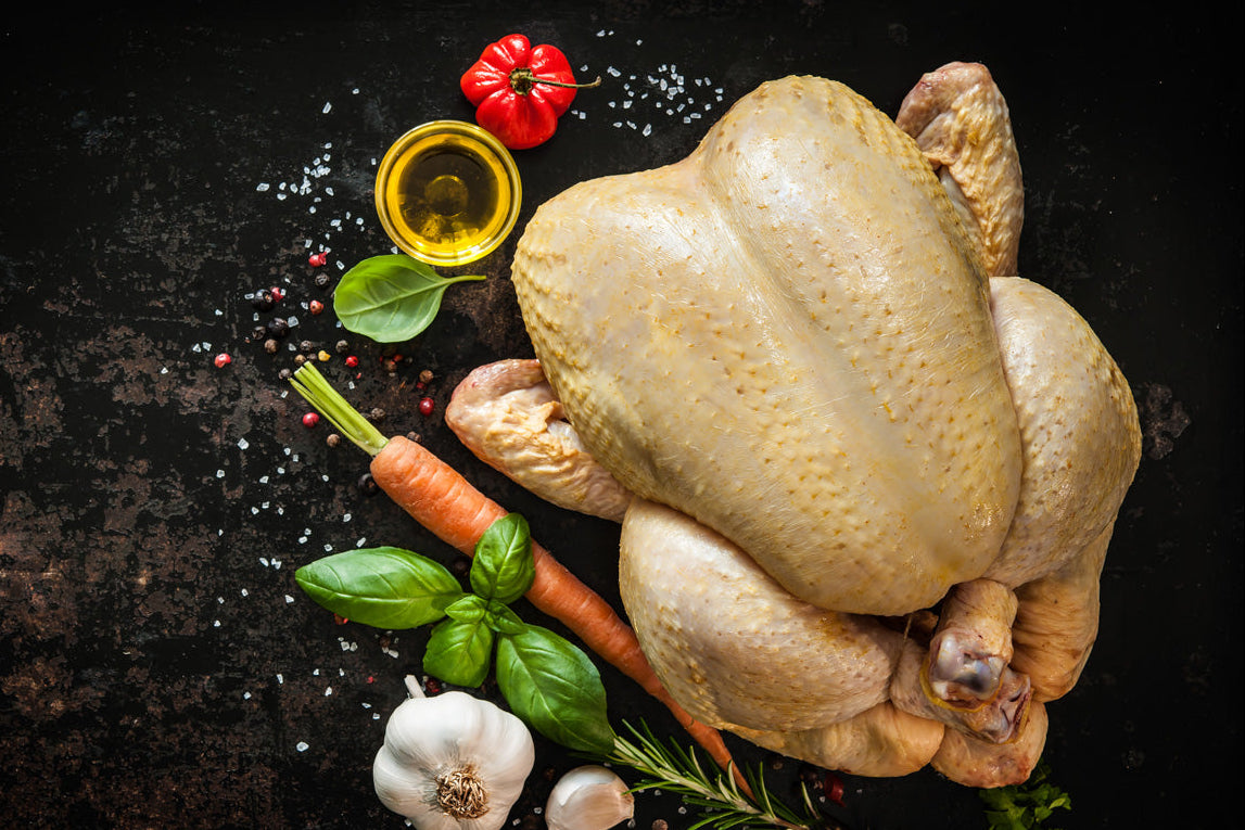 Raw chicken with vegetables on a dark surface