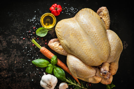 Raw chicken with vegetables on a dark surface